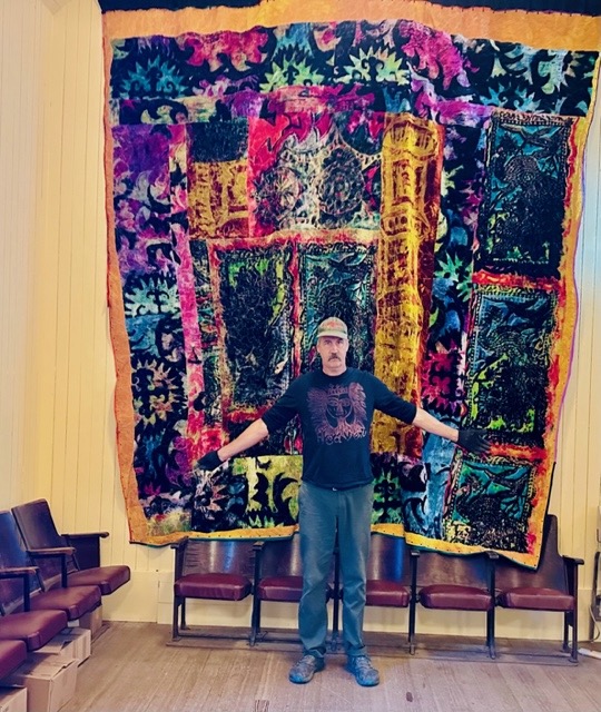 Krist in front of tapestry.