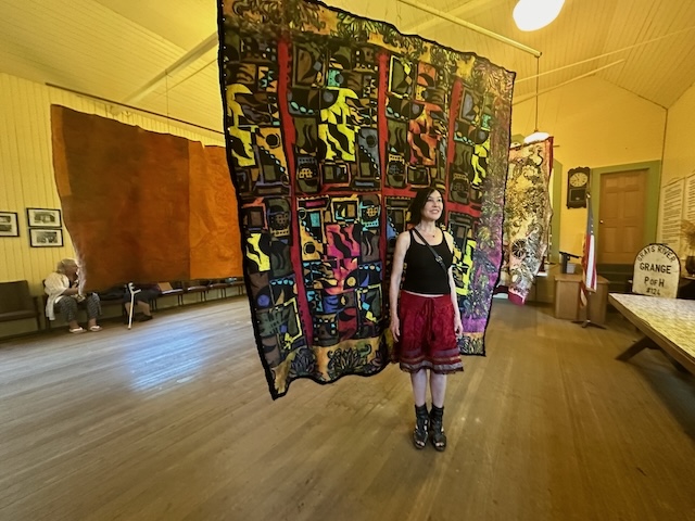 Darka in front of tapestry.